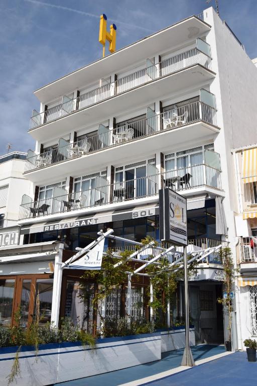 a large white building with balconies and a traffic light at Hotel Ampolla Sol in L'Ampolla