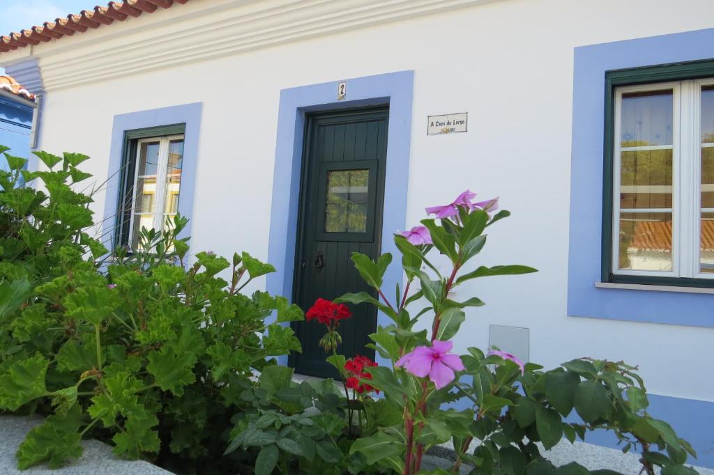 una casa bianca con una porta nera e fiori di Casa do Largo ad Alcácer do Sal