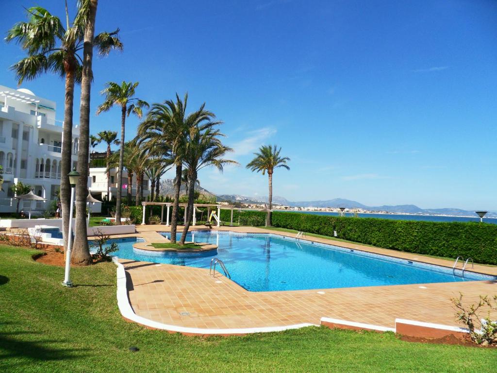 una piscina con palmeras en un complejo en Cala d'Or, en Denia