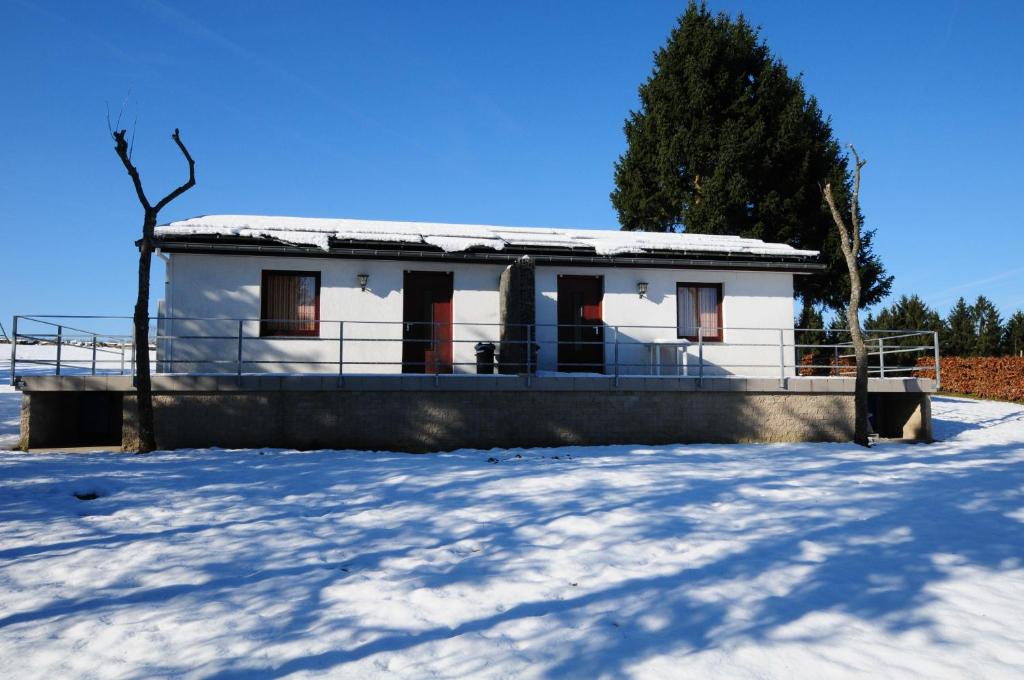 une maison blanche avec de la neige au sol dans l'établissement Apartment " PENSCH ", à Wilwerwiltz