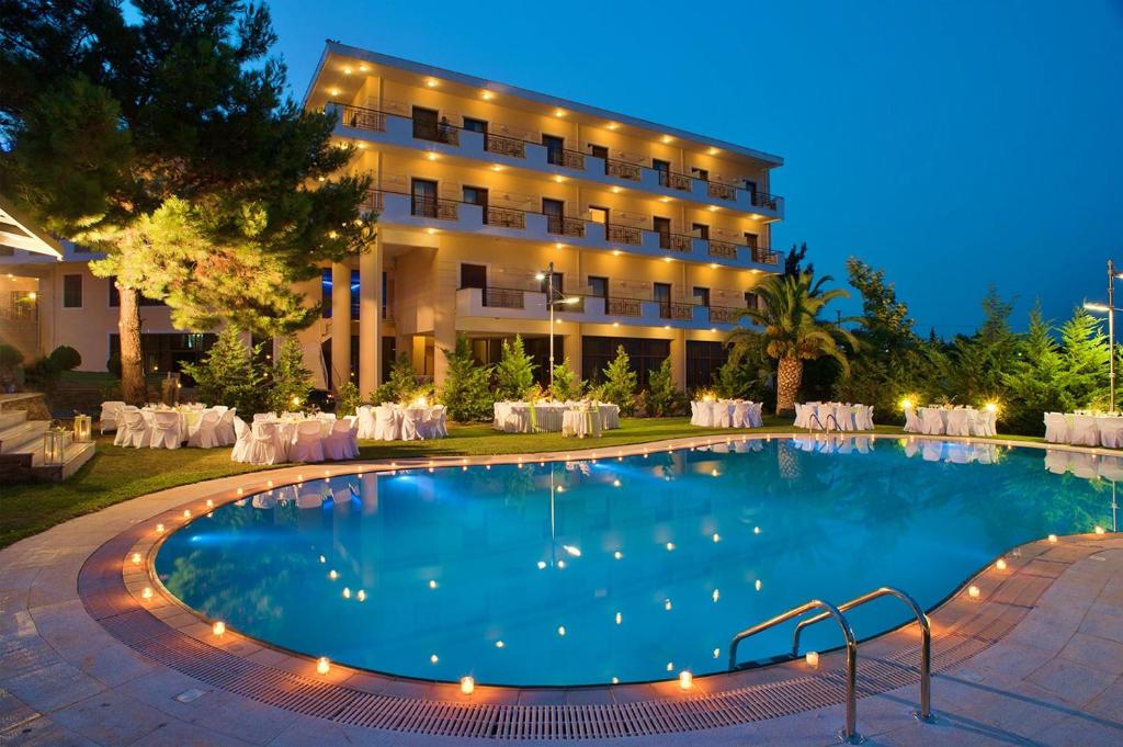 a pool in front of a hotel at night at Parnis Palace in Athens