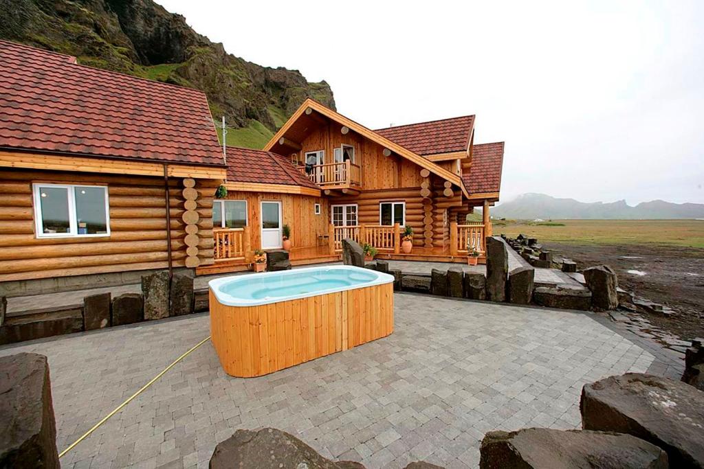 Cabaña de madera con bañera de hidromasaje frente a ella en Welcome Lambafell, en Eyvindarhólar