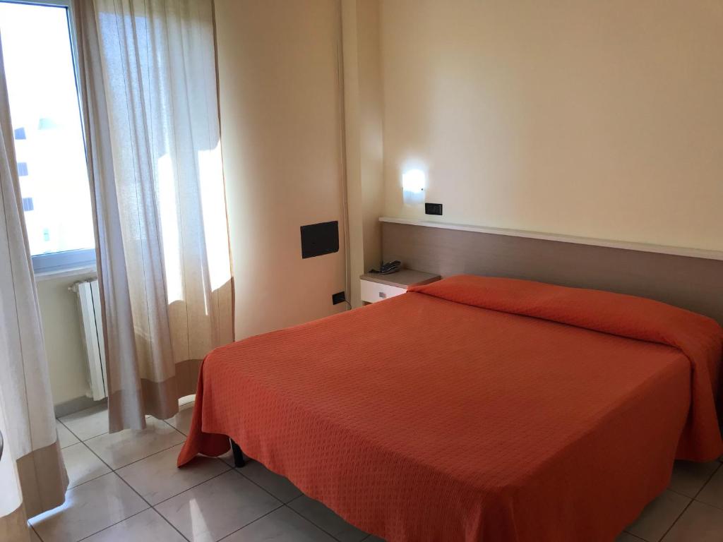 sypialnia z pomarańczowym łóżkiem i oknem w obiekcie Hotel San Luca w mieście Rossano