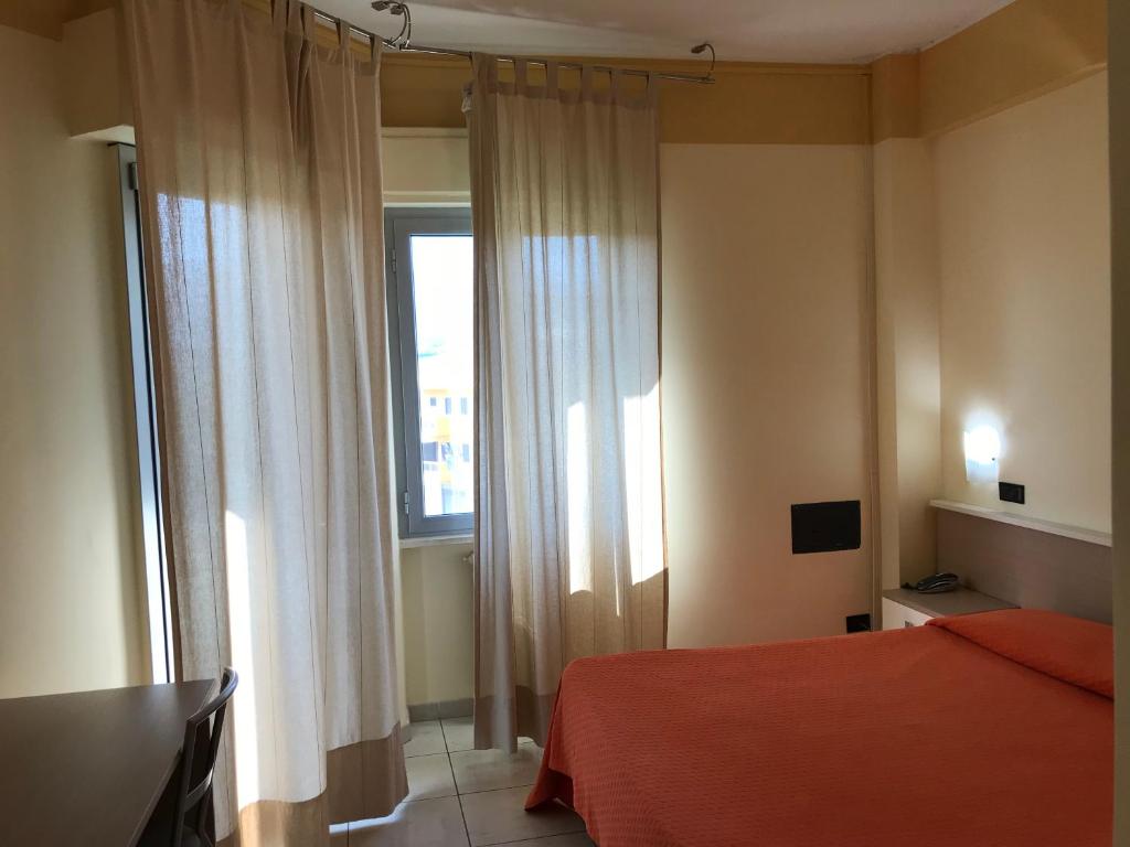 una camera con letto rosso e finestra di Hotel San Luca a Rossano