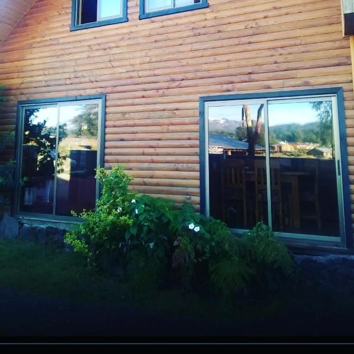 2 finestre sul lato di una casa in legno di Hostal Andalue a Puerto Fuy