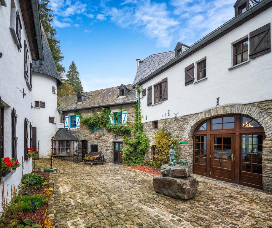 uma vista exterior de uma casa com um pátio de pedra em Domaine du Moulin d'Asselborn em Asselborn