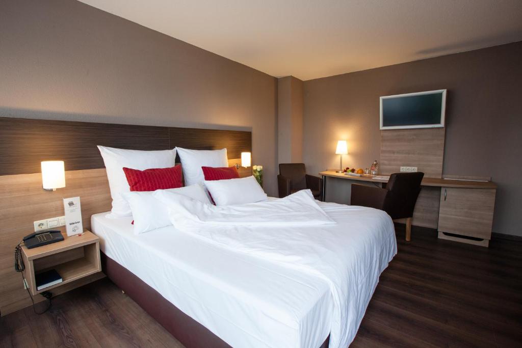 a hotel room with a large bed and a desk at Centro Hotel U-NO 1 in Großbettlingen