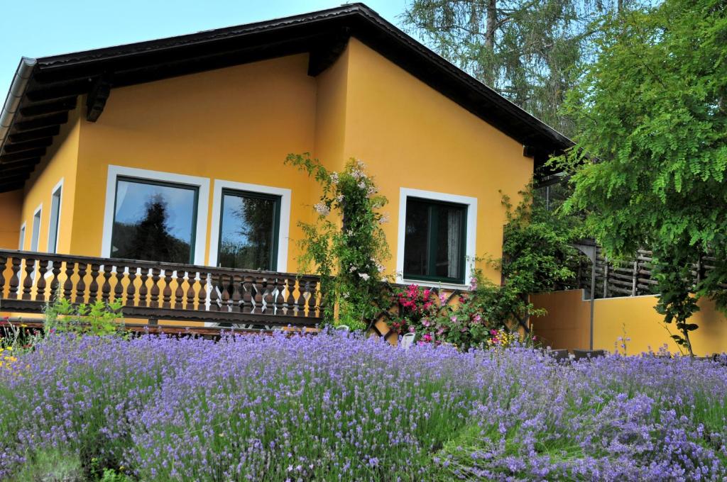 uma casa com um campo de flores roxas em frente em Sulamith Ferienhaus mit Garten em Sankt Kathrein am Offenegg