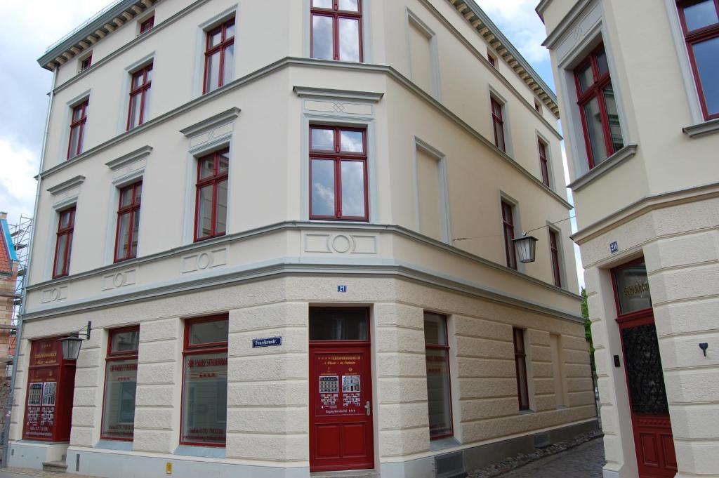 ein weißes Gebäude mit roten Türen auf einer Straße in der Unterkunft Haus Steuerrad in Stralsund