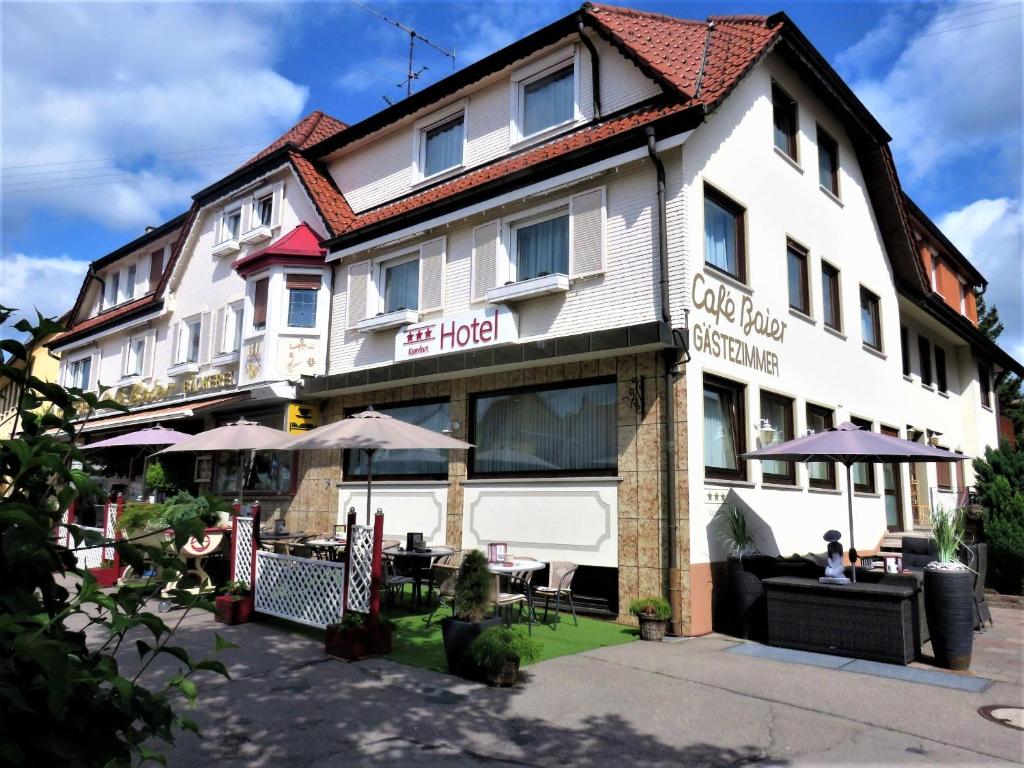 een groot wit gebouw met tafels en parasols bij Hotel Conditorei Cafe Baier in Schömberg