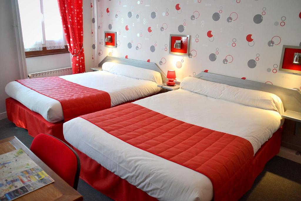 two beds in a hotel room with red and white sheets at Hotel Angleterre in Cherbourg en Cotentin