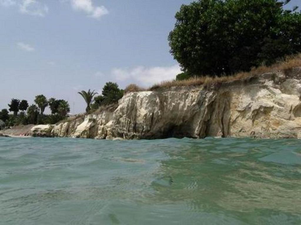 an island in the water next to a rocky shore at Il Mirto E La Rosa in Arenella