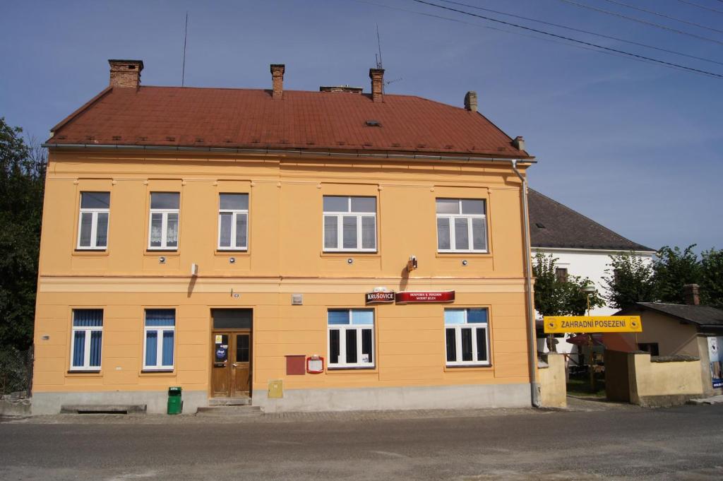 a yellow building with a brown roof at Penzion Modrý Jelen in Vidnava