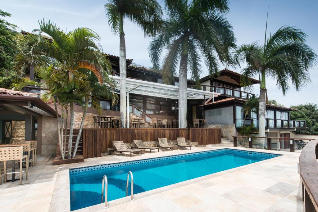 a house with a swimming pool and palm trees at Ilha Branca Exclusive Hotel in Búzios