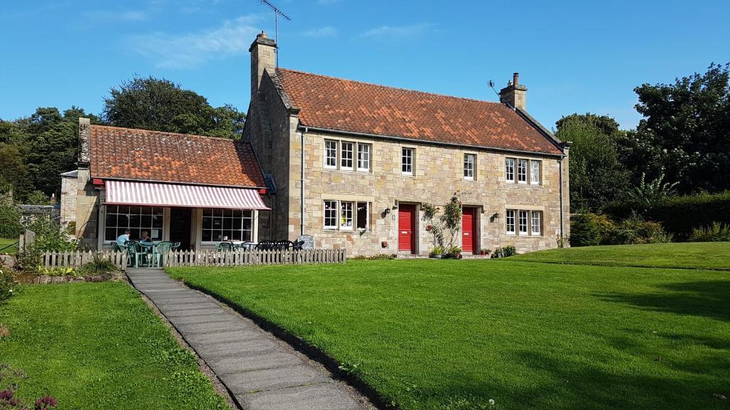 un gran edificio de piedra con una puerta roja y un patio de césped en Ford Village Bed & Breakfast, en Ford