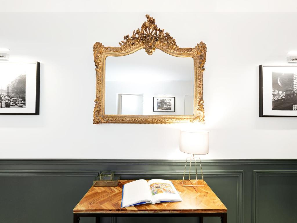 a mirror and a table with a book and a lamp at LivinParis - Luxury 3 Bedrooms République I in Paris