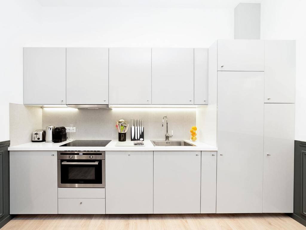 a white kitchen with white cabinets and a sink at LivinParis - Luxury 3 Bedrooms République I in Paris