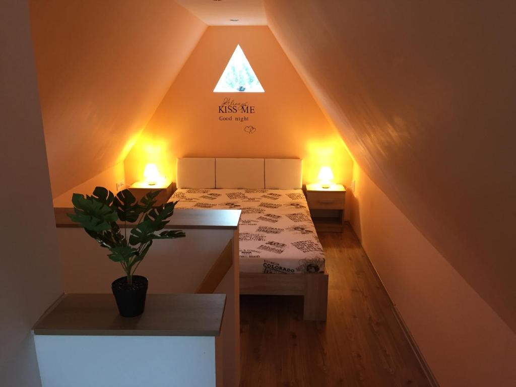 a small attic room with a bed and two lights at Izabella Vendégház Somló in Doba