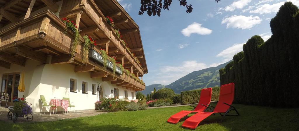 two red chairs sitting in a yard next to a building at Sportpension Christina by PiaundDirk in Fügen