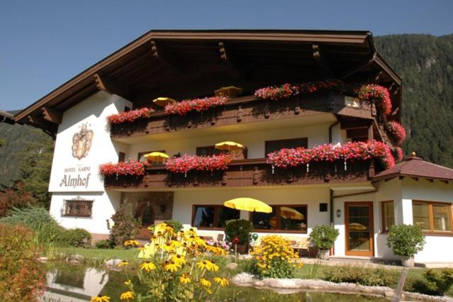 un edificio con flores y sombrillas delante de él en Hotel-Garni Almhof, en Mayrhofen