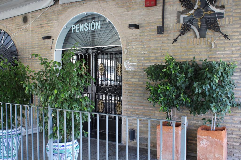 una entrada a un edificio con dos macetas en Pensión Hidalgo 2, en Utrera