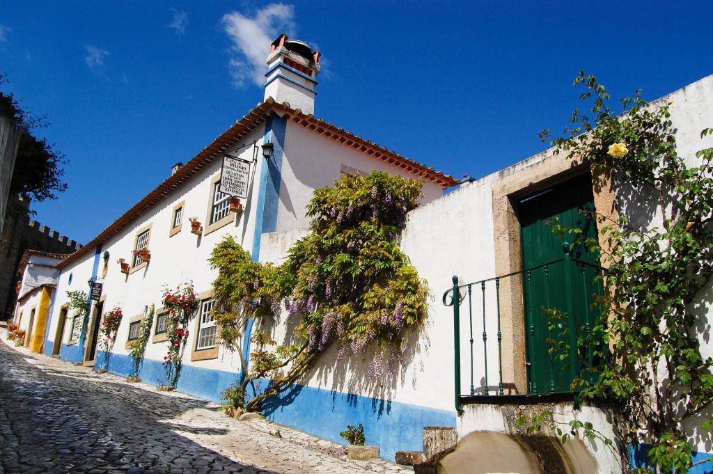 a white and blue building with a green door at Casa Do Relogio in Óbidos