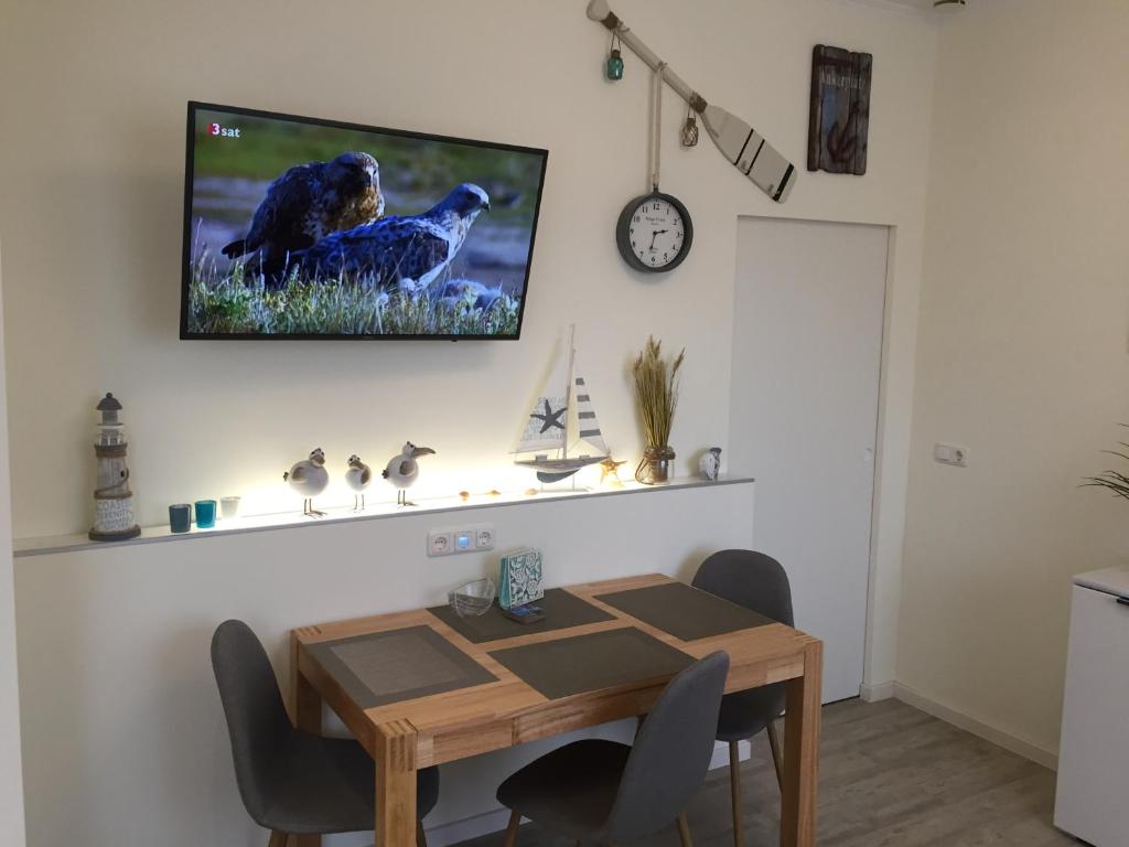 ein Esszimmer mit einem Tisch und einem TV an der Wand in der Unterkunft Haus Solymar App. 18 in Grömitz