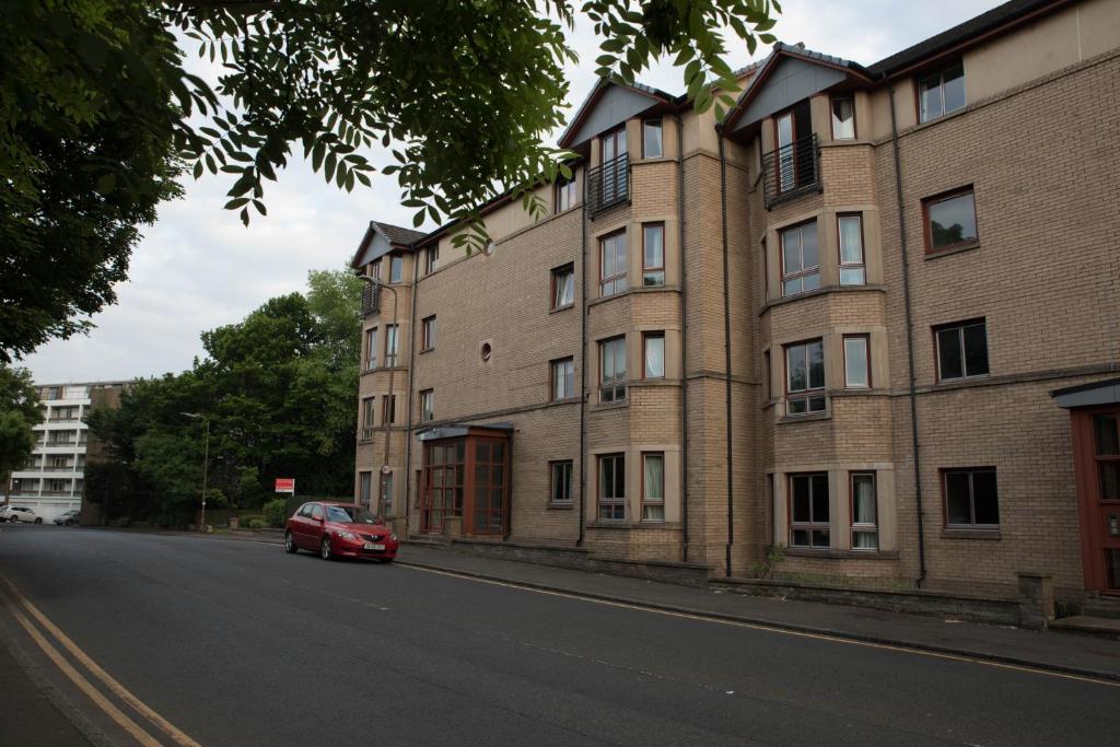 een rode auto geparkeerd voor een bakstenen gebouw bij South Groathill - Lovely 2 bed with Castle View in Edinburgh