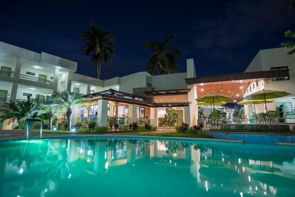 a swimming pool in front of a building at night at Hotel Palace Inn in Tuxtla Gutiérrez