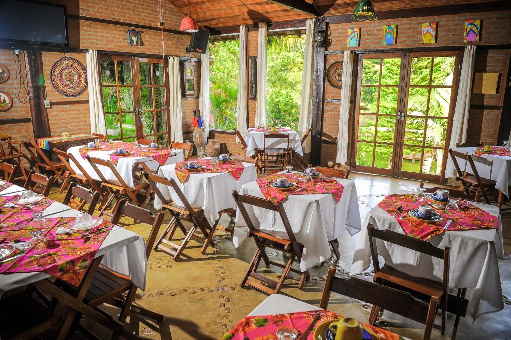 Encantos do Vale Pousada e SPA Cultural في بوينو برانداو: غرفة طعام مع طاولات وكراسي في مبنى