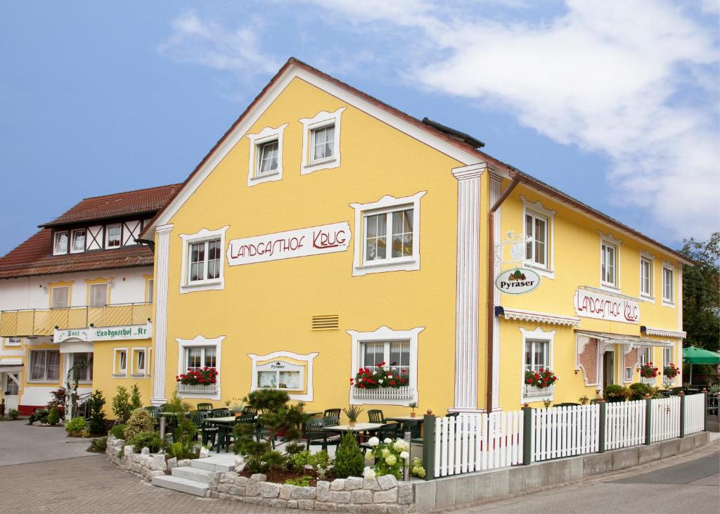 a yellow building with tables in front of it at Landgasthof Krug in Dechendorf
