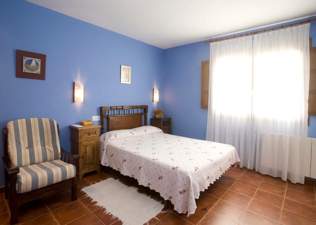 1 dormitorio con 1 cama, 1 silla y 1 ventana en Hotel Rural Suquin en Navia