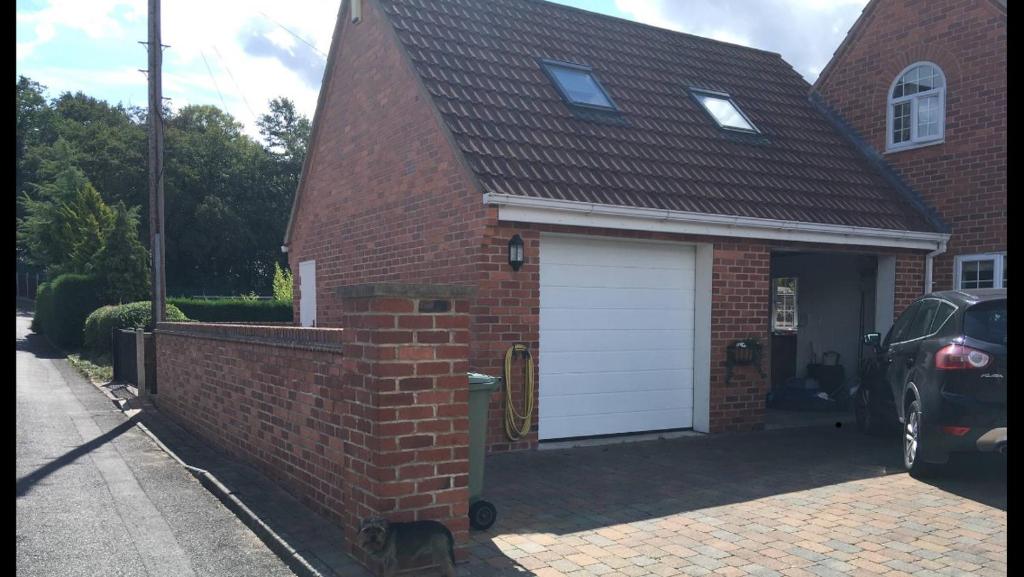 a red brick house with a white garage at The Loft in Hollingwood