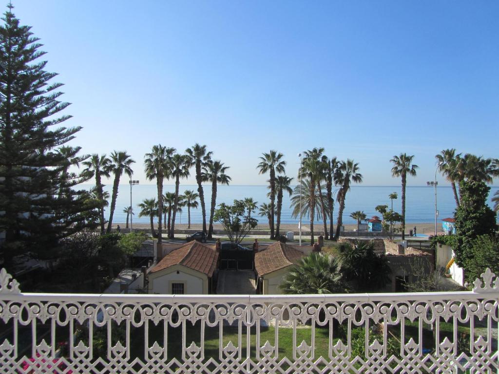 uma varanda com vista para a praia e para as palmeiras em Villa Amalia Suites Malaga em Málaga