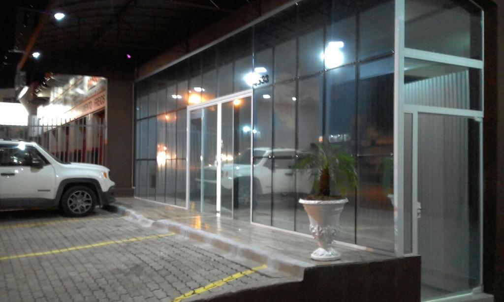 a glass facade of a building with a potted plant at Rocha's Hotel in Guarapuava