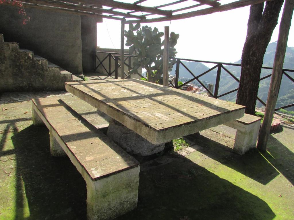um banco de madeira sentado em cima de um edifício em Rifugio dei tre Pini em Castelmola