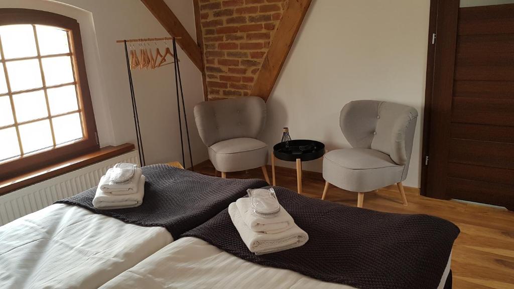 a bedroom with two chairs and a bed with shoes on it at Miodosytnia in Chwarszczany