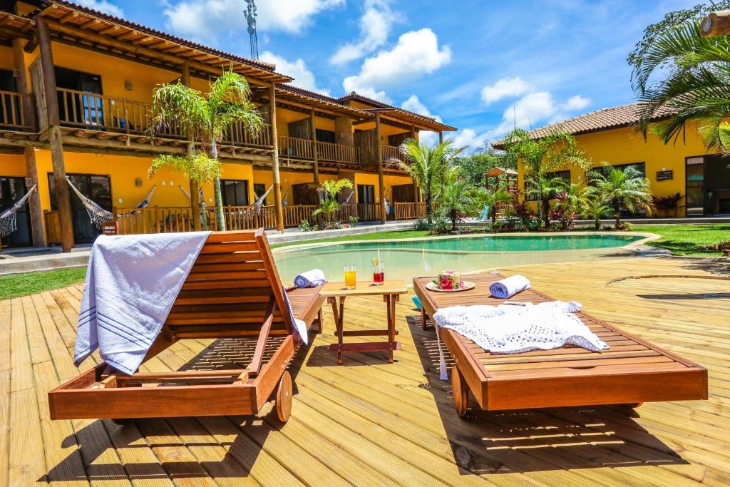 un patio con 2 sillas y una mesa junto a la piscina en Pousada Tropicarim, en Itacimirim