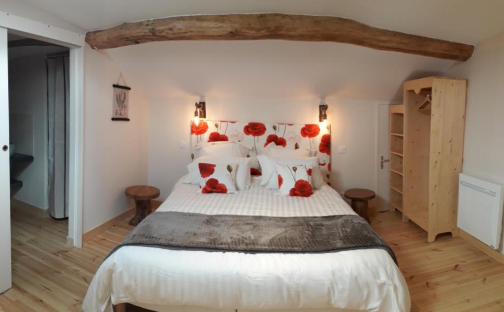 une chambre avec un grand lit blanc avec des oreillers rouges dans l'établissement La chenevière, à Saint-Rémy-de-Chargnat