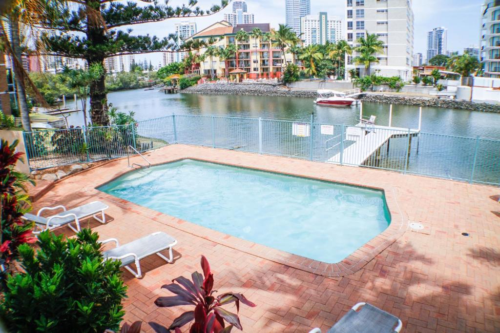 una piscina con sillas y un cuerpo de agua en Surfers Riverside, en Gold Coast