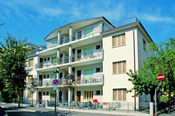 un gran edificio blanco con balcón en una calle en Residenza Valcris, en Lignano Sabbiadoro