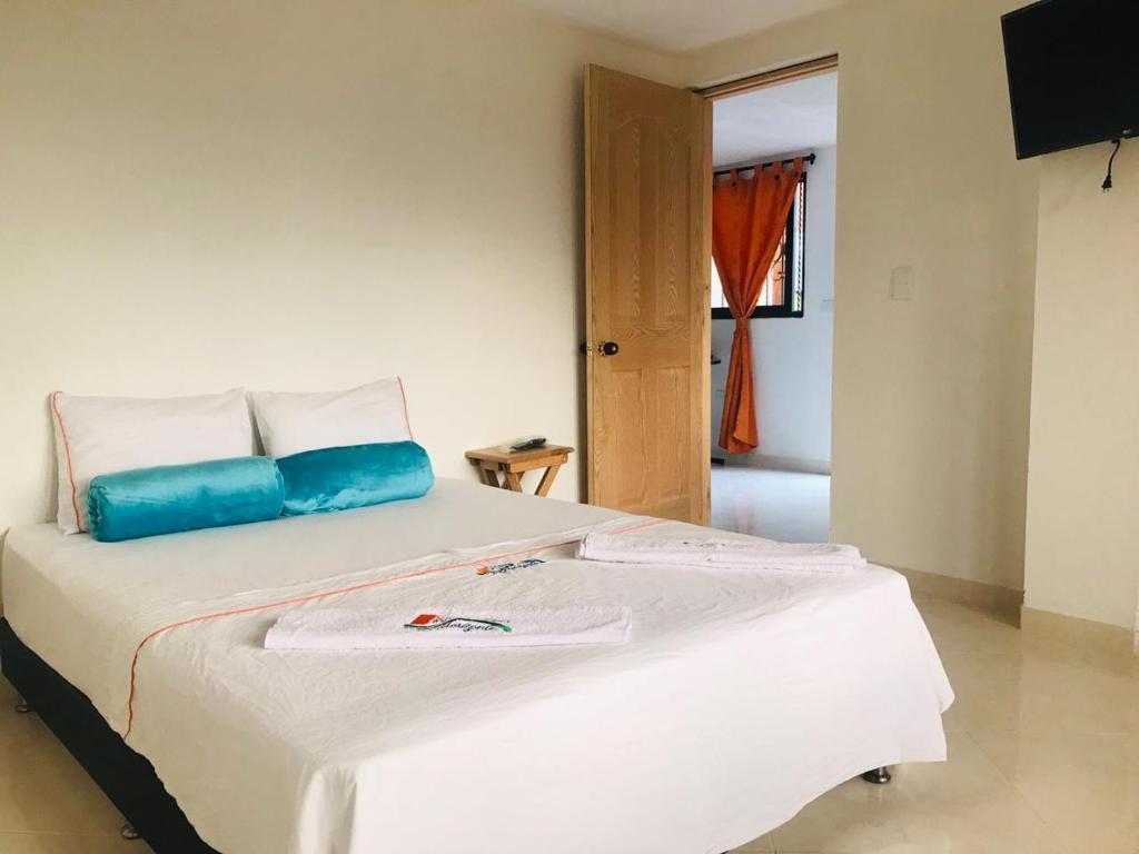 sypialnia z białym łóżkiem i niebieską poduszką w obiekcie Apartahotel El Horizonte w mieście Guatapé