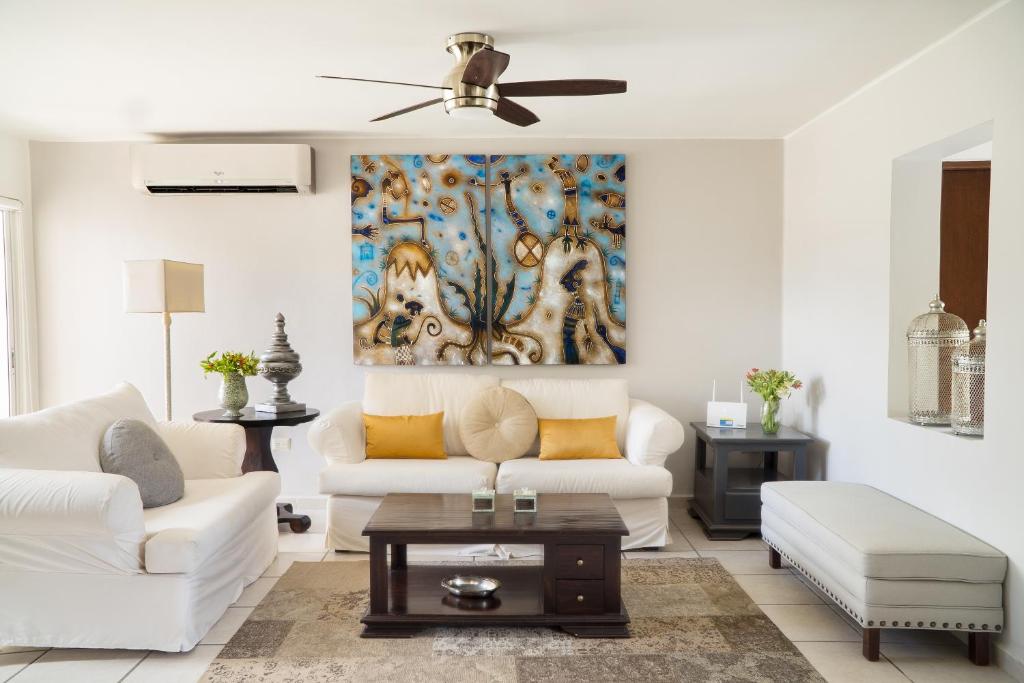 a living room with white furniture and a painting on the wall at CASA CACTO en San Jose del Cabo in San José del Cabo