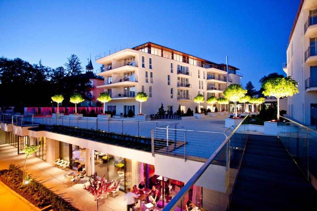 a building with people sitting outside of it at night at Lake's - My Lake Hotel in Pörtschach am Wörthersee