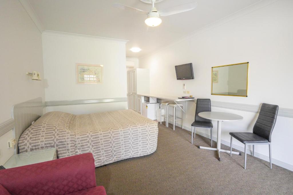 een slaapkamer met een bed en een tafel en stoelen bij Centretown Motel in Nagambie