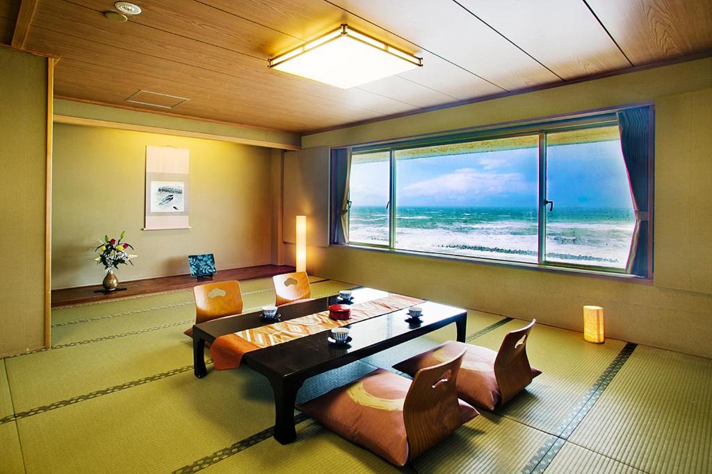 a living room with a table and chairs and a view of the ocean at Senami View Hotel in Senami
