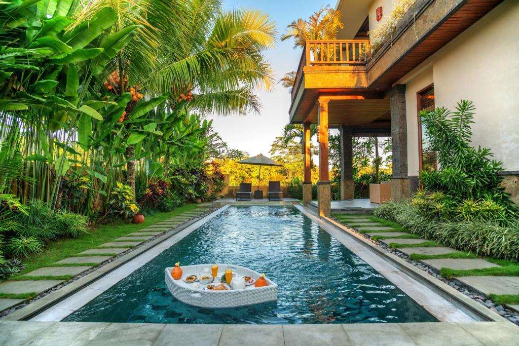 a pool in a house with a boat in the water at Alosta Luxury Private Villa in Ubud