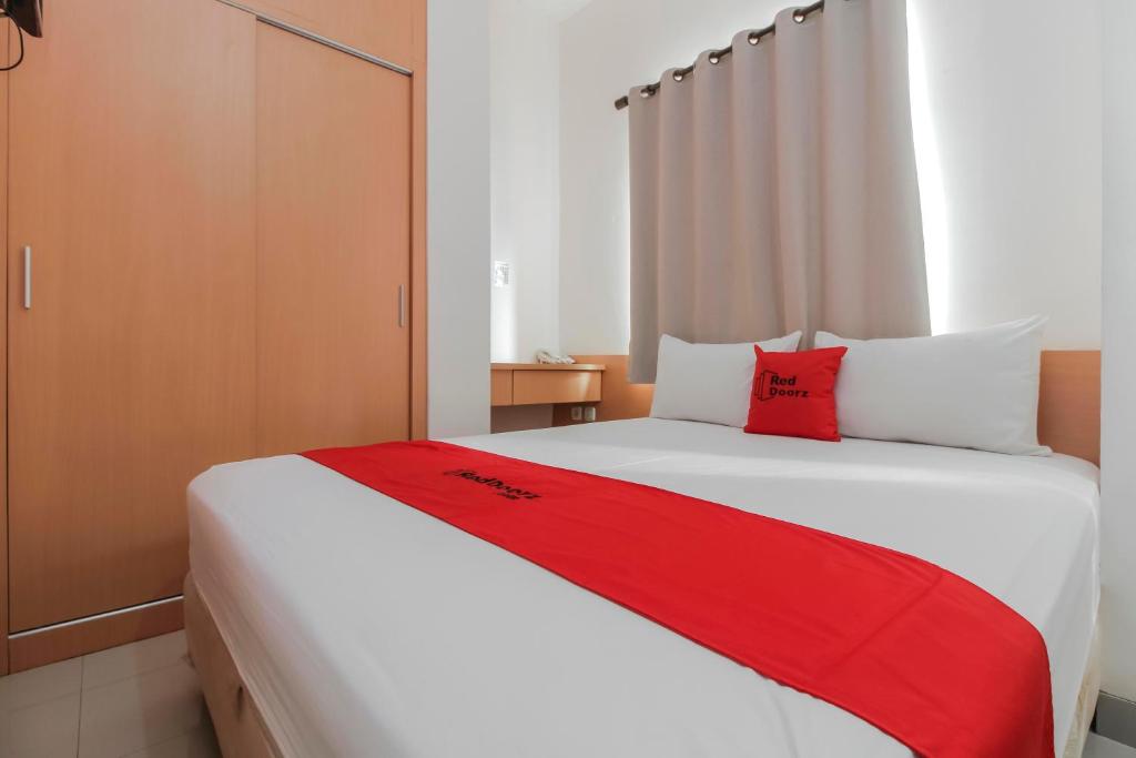 1 dormitorio con 1 cama blanca grande con almohadas rojas en RedDoorz Plus near Galaxy Bekasi, en Bekasi