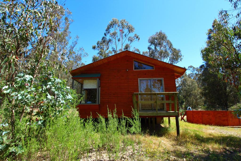 una pequeña casa roja en medio de un campo en Cabaña Vintage, en Algarrobo
