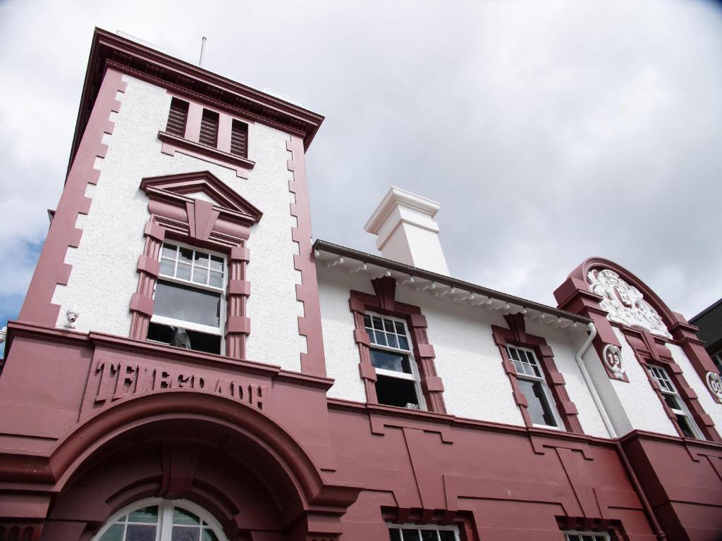 un edificio rojo y blanco con un reloj en él en Clarence Boutique Hotel en Tauranga